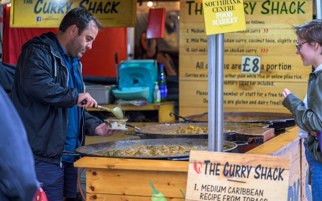 LONDON - May 20, 2022: Man serves customer curry at pop up street food stall on South Bank