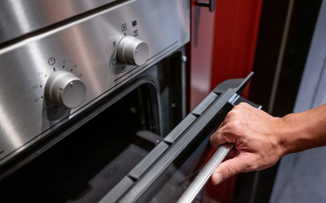 Male Hand Opening Oven Door In The Kitchen Showroom. Buying Cook